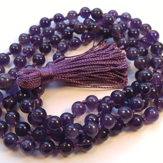Purple beaded necklace with a tassel on a white background