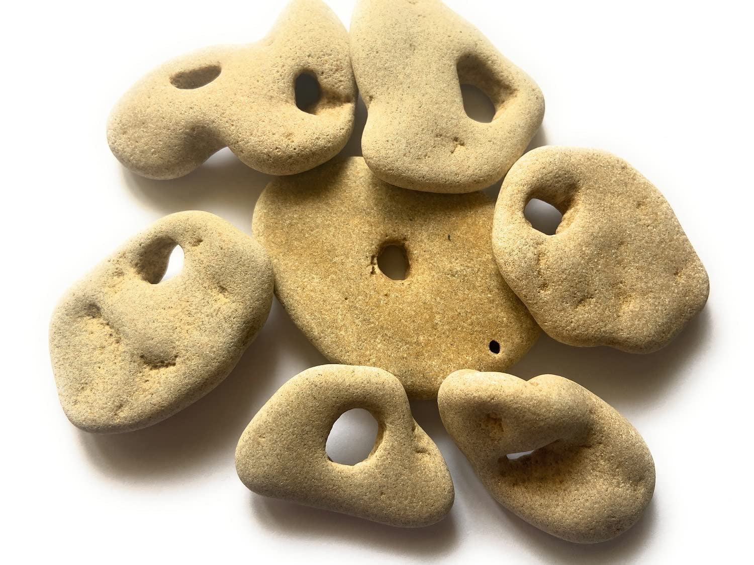 Set of sandstone pebbles with holes on a white background