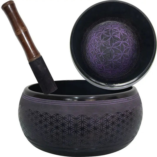 Black singing bowl with a wooden mallet on a white background