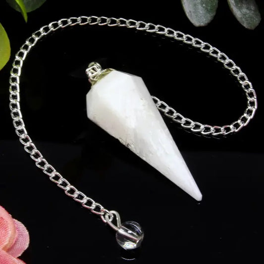 White crystal pendulum on a silver chain against a dark background