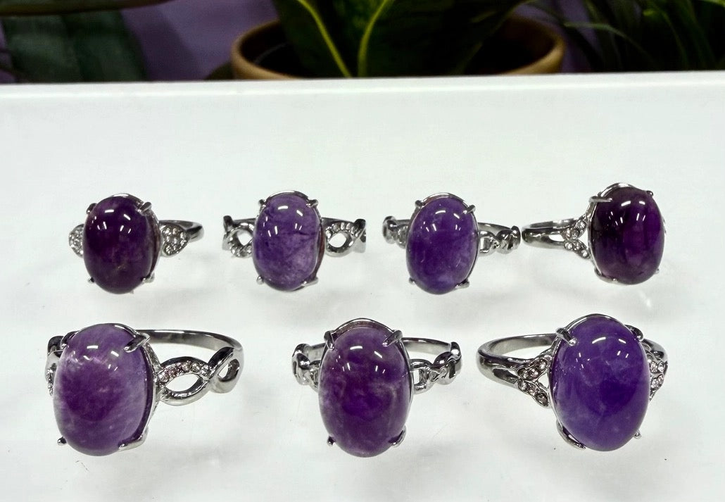 Set of purple gemstone rings with silver settings on a white surface.