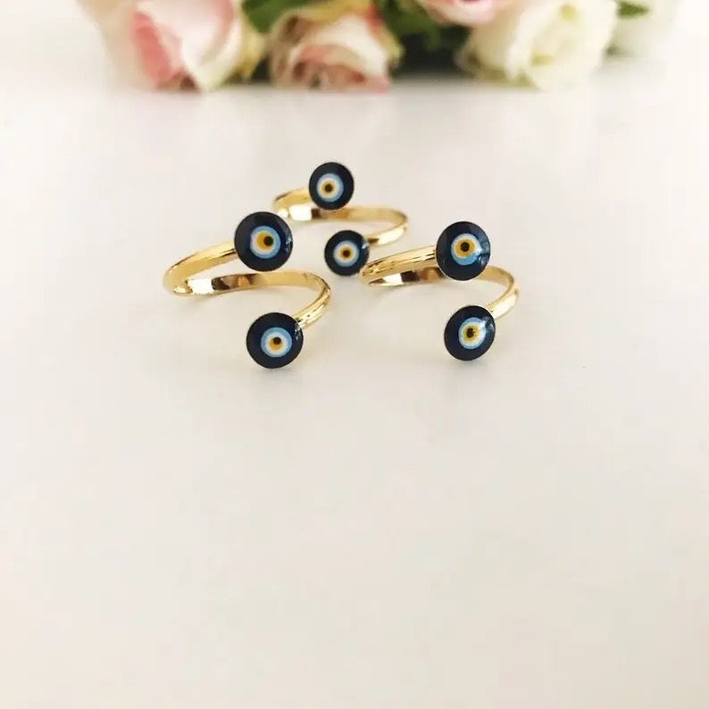 Gold rings with black and blue eye designs on a light background