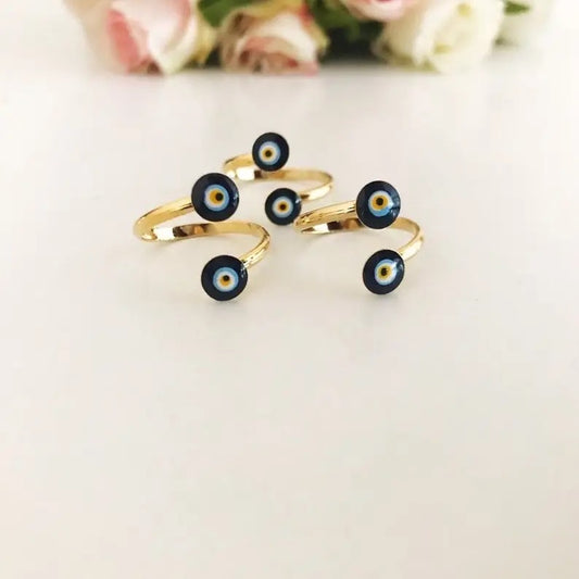 Gold rings with black and blue eye designs on a light background
