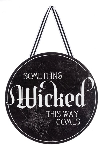 Round black sign with 'Something Wicked This Way Comes' text and spider web design on a white background