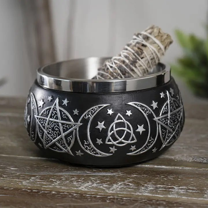 Black incense bowl with silver designs on a wooden surface, containing sage.