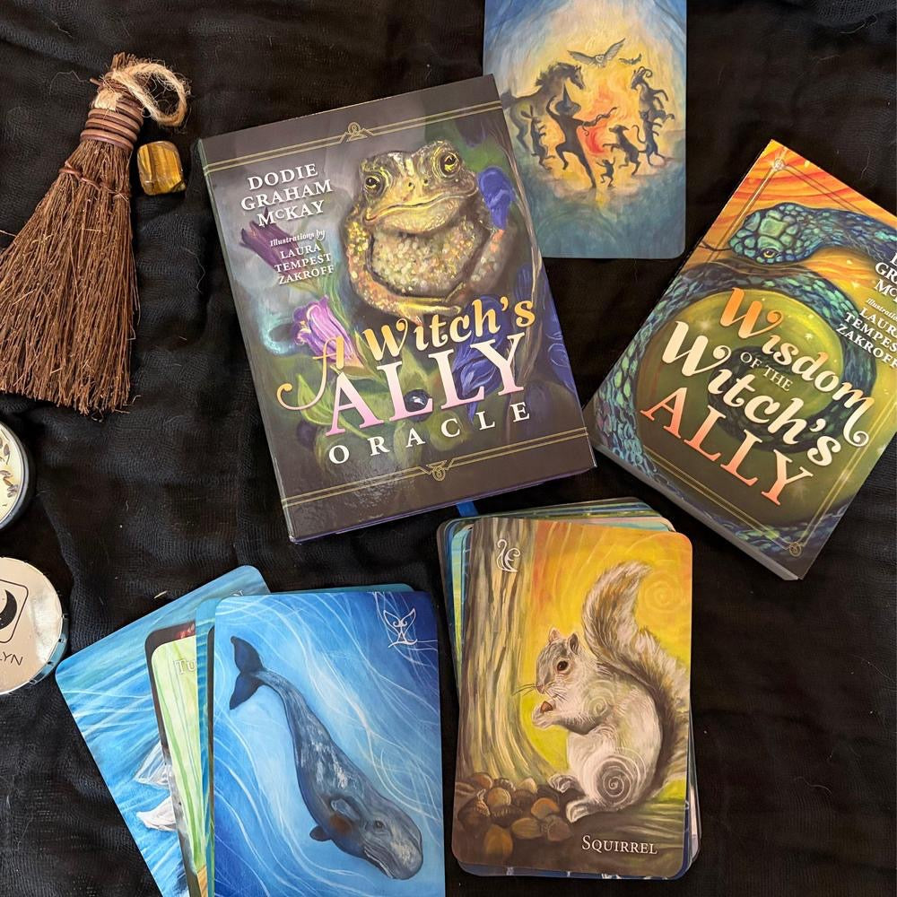 Witch's Ally Oracle cards and broom on a dark fabric background