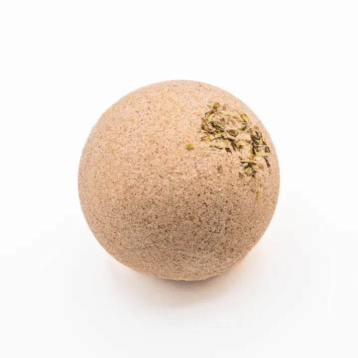 Round beige bath bomb with greenery on a white background