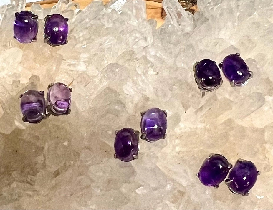 Five pairs of amethyst earring studs on a white crystal