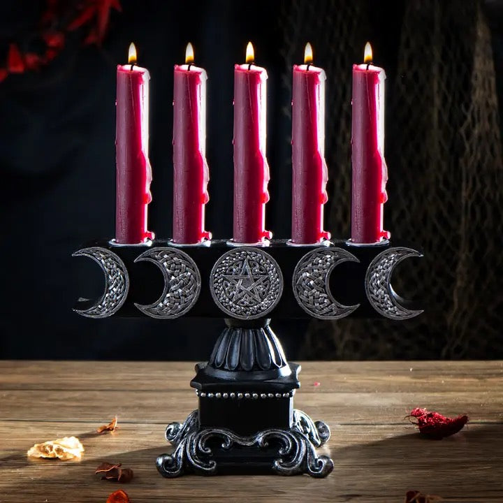 Candle holder with five pink candles and a pentagram design on a dark background