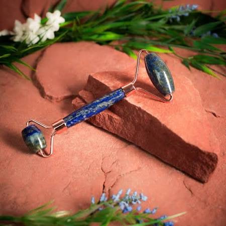 Lapis lazuli massage roller on red brick with flowers