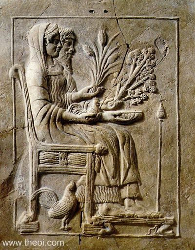 Ancient stone relief carving depicting a seated woman holding a plant and fruit, with a bird at her feet, shown in a square frame on a textured stone surface. Persephone and Hades sit enthroned in the underworld. The goddess holds a hen and a sheaf of wheat, and the god a phiale cup and frond of asphodel. Their throne is decorated with a rooster.
