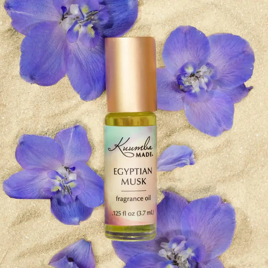 Roll-on bottle of Egyptian Musk fragrance oil with purple flowers on a beige background