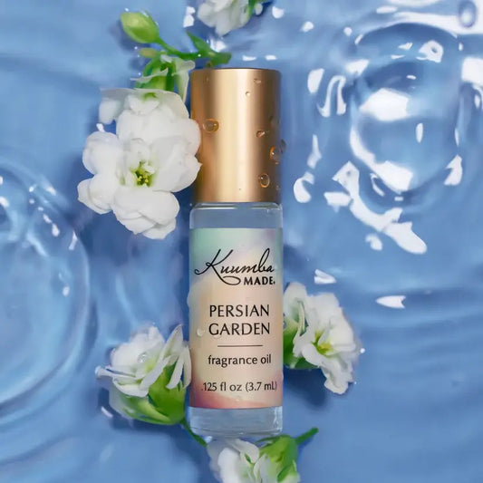Perfume bottle labeled 'Persian Garden' by Krumelure with white flowers on a blue water background