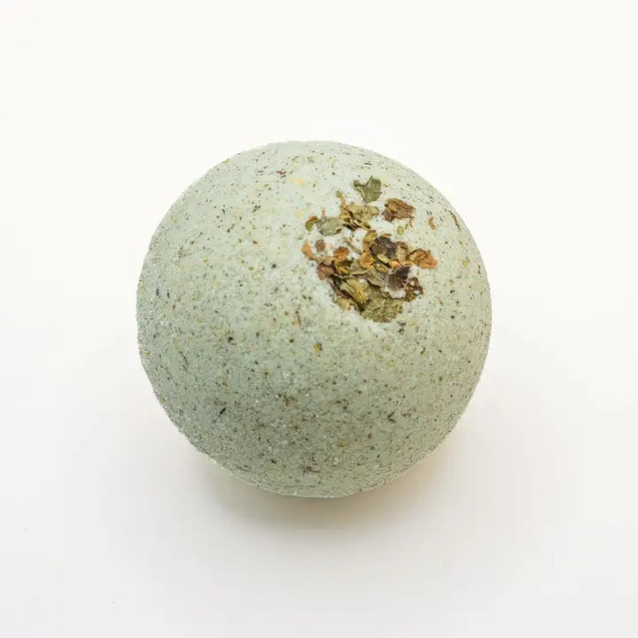 Green bath bomb with herbs on a white background