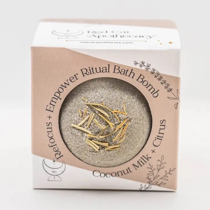 Bath bomb packaging with text and a small bath bomb visible through the clear window.