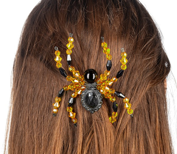 Decorative spider hair clip with yellow and black beads on a person's hair.