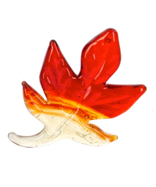Glass sculpture of a leaf with red, orange, and clear colors on a white background