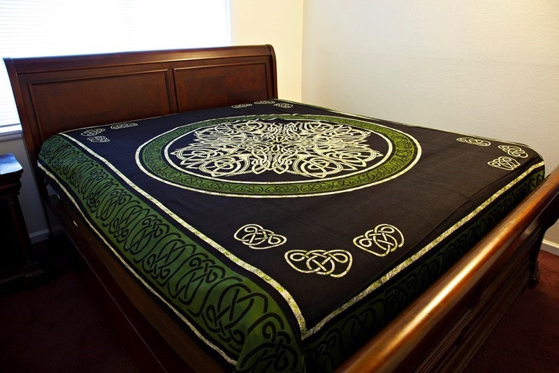 A dark brown and green Celtic patterned quilt or comforter spread across a wooden bed frame in a bedroom setting.