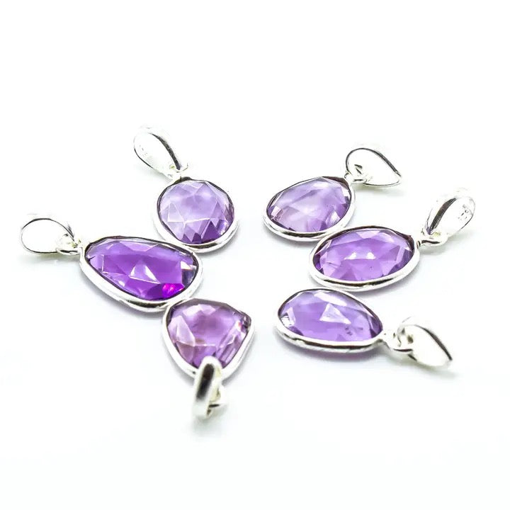 Purple teardrop pendants on silver hooks against a white background