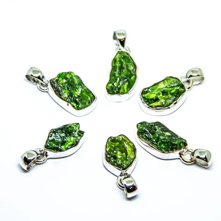 Set of six green stone pendants with silver settings on a white background