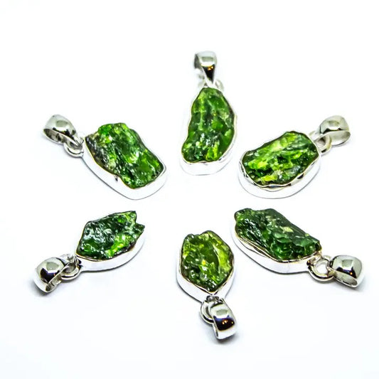 Set of six green stone pendants with silver settings on a white background