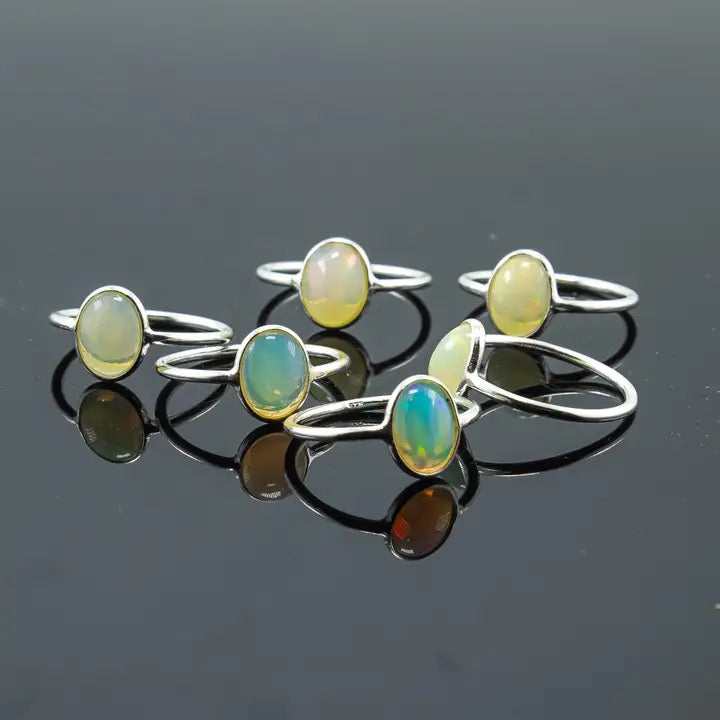 Set of opal rings on a reflective black surface