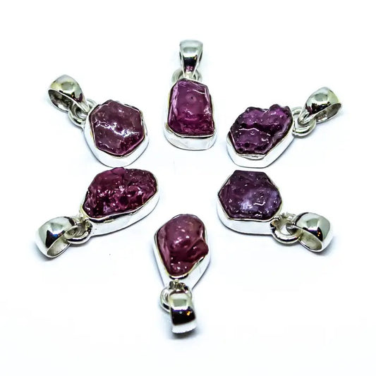 Set of six purple gemstone pendants with silver settings on a white background