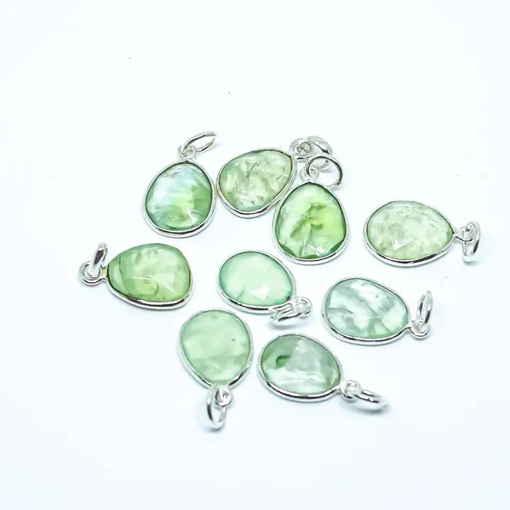 Green gemstone pendants with silver settings on a white background