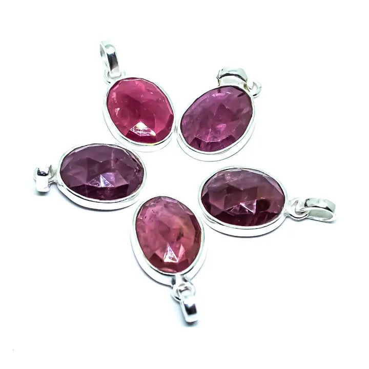 Set of four pink gemstone pendants on silver chains against a white background