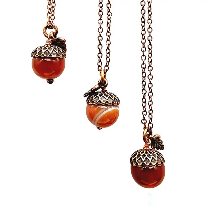 Three acorn-shaped pendants on chains against a white background
