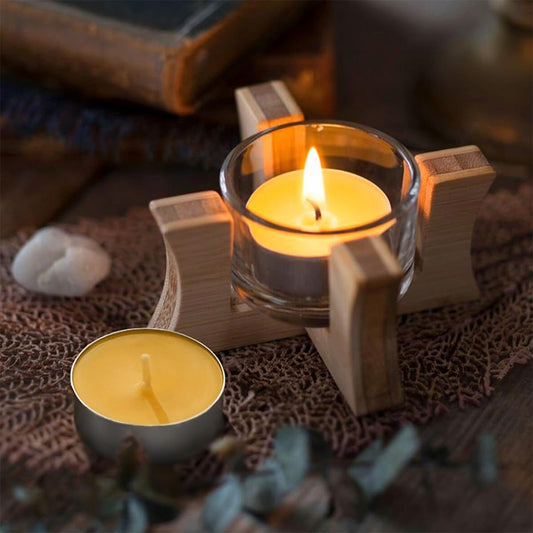 One candle in a glass holders one unlit on a textured surface with a blurred background