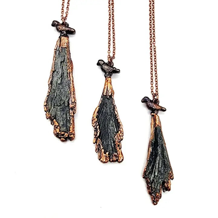 Three pendant necklaces with unique designs on a white background