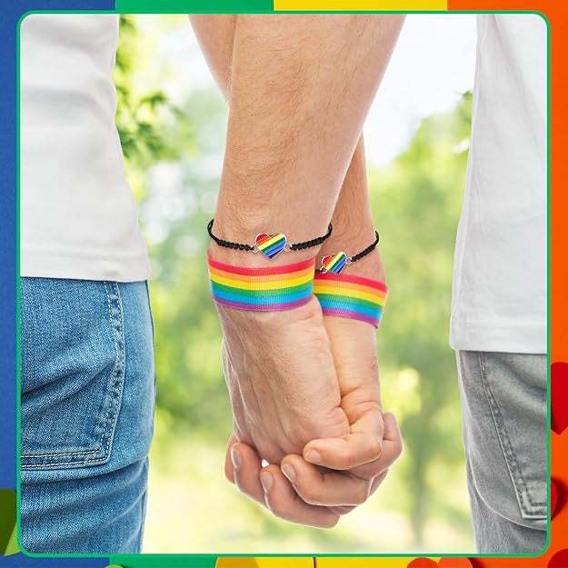 Two people holding hands with rainbow wristbands against a blurred green background