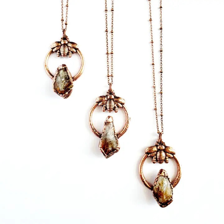 Three gold necklaces with pendant stones on a white background