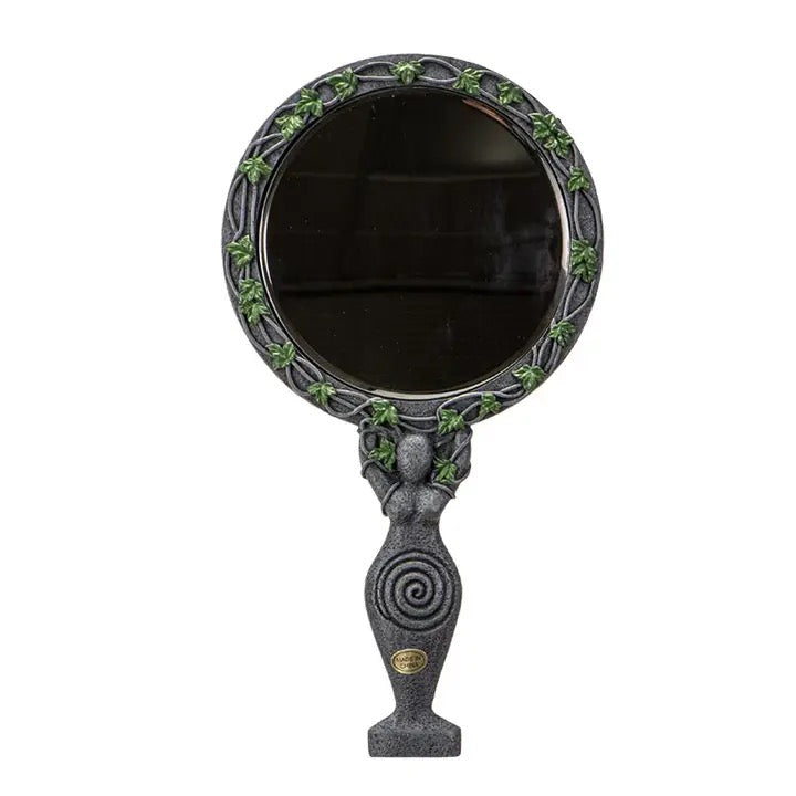 Decorative hand mirror with green leaf patterns on a white background