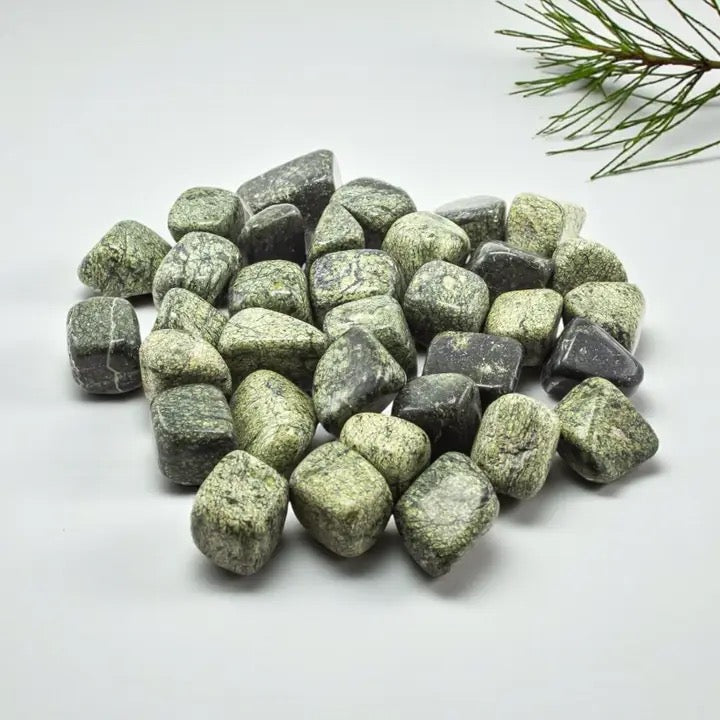 Green and gray stones on a white background with a branch in the corner
