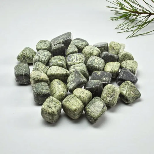 Green and gray stones on a white background with a branch in the corner
