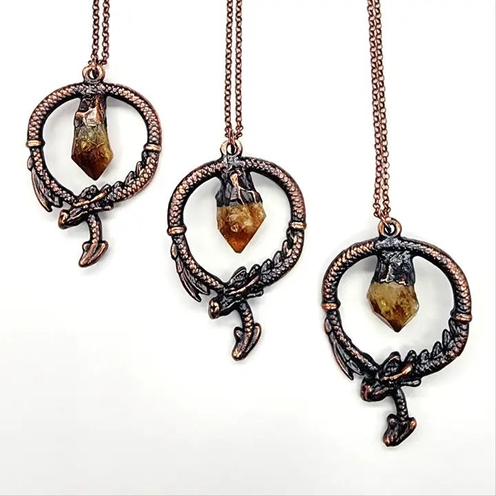 Three ornate necklaces with gemstone pendants on a white background