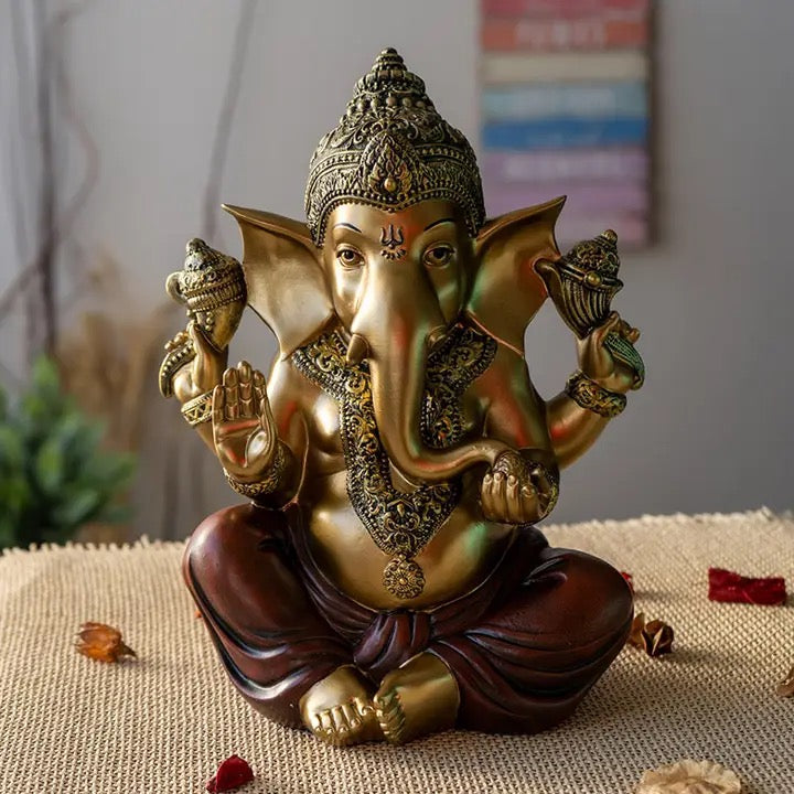 Decorative statue of a seated figure with elephant head on a textured surface.