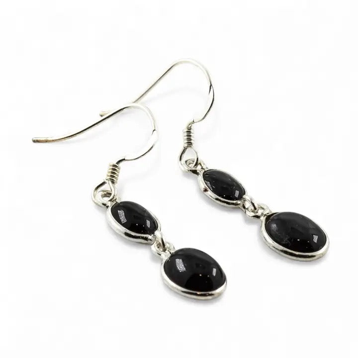 Black stone drop earrings on silver hooks against a white background