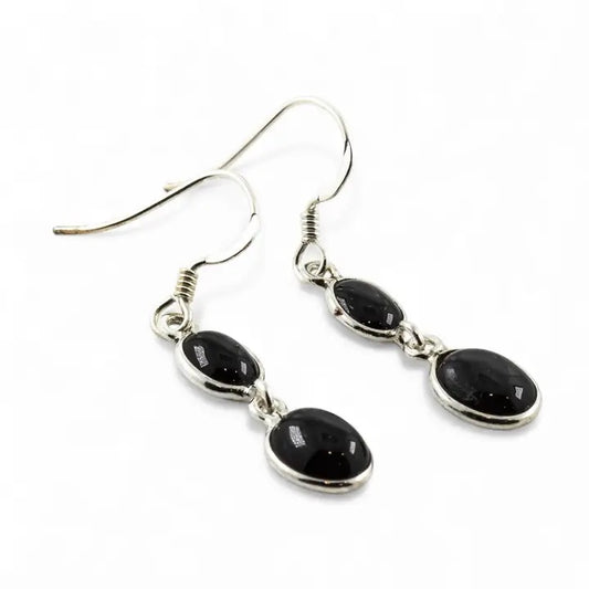 Black stone drop earrings on silver hooks against a white background
