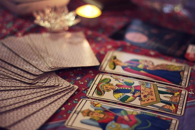 Image of three Tarot cards on a table with a card curve stack.