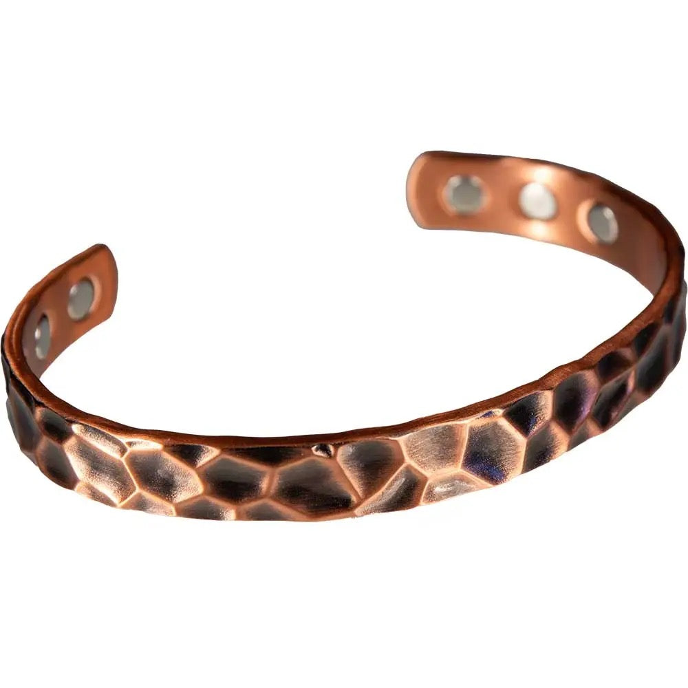 Copper bracelet with a textured pattern on a white background