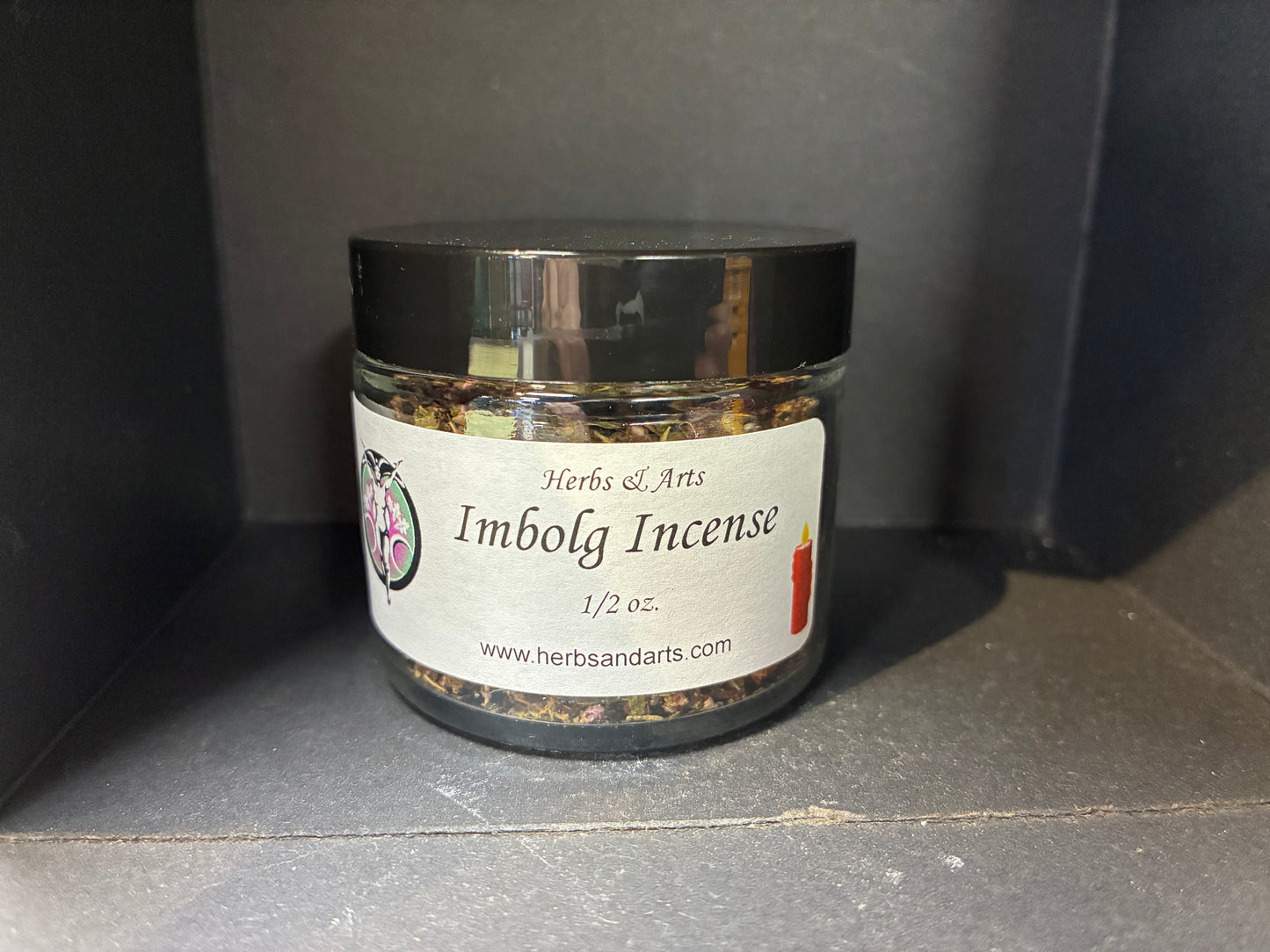 Jar of Imbolg Incense with a label on a dark surface