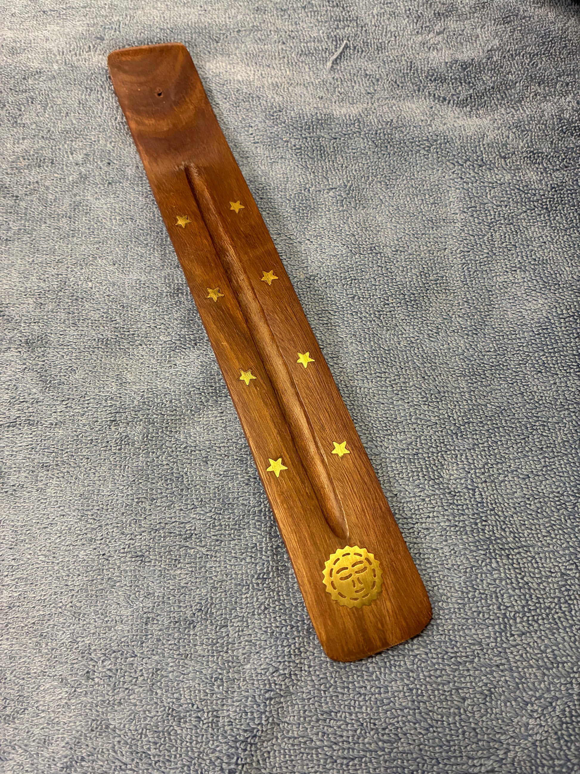 Wooden incense stick holder with star designs on a gray fabric background