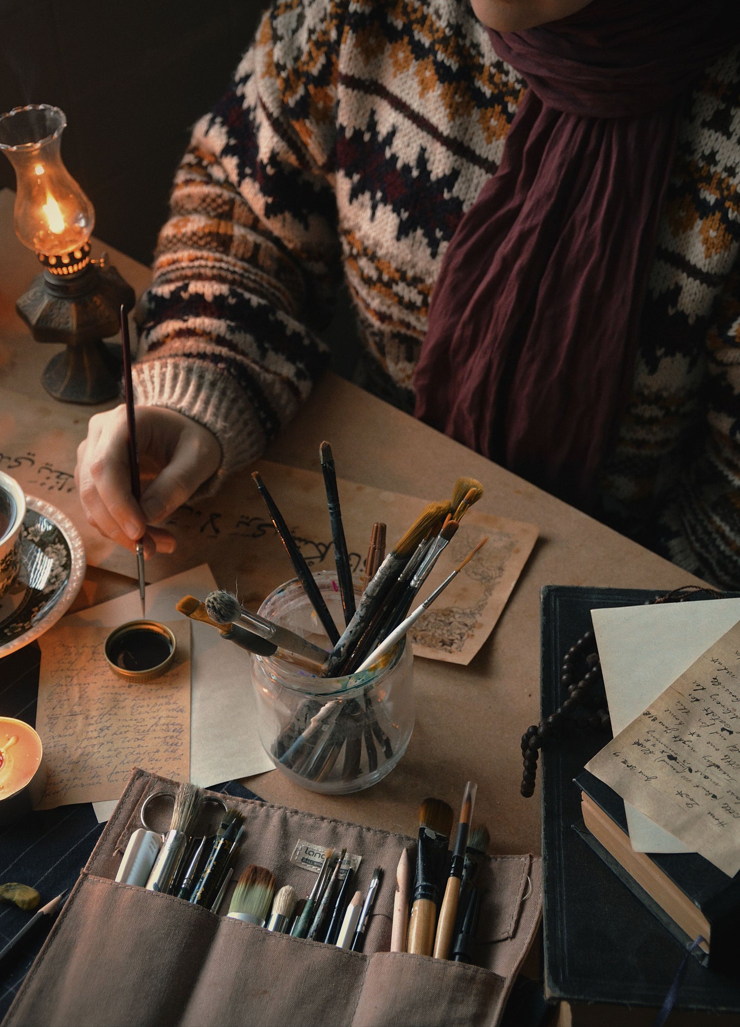 Person with painting supplies at a table with a warm, cozy atmosphere