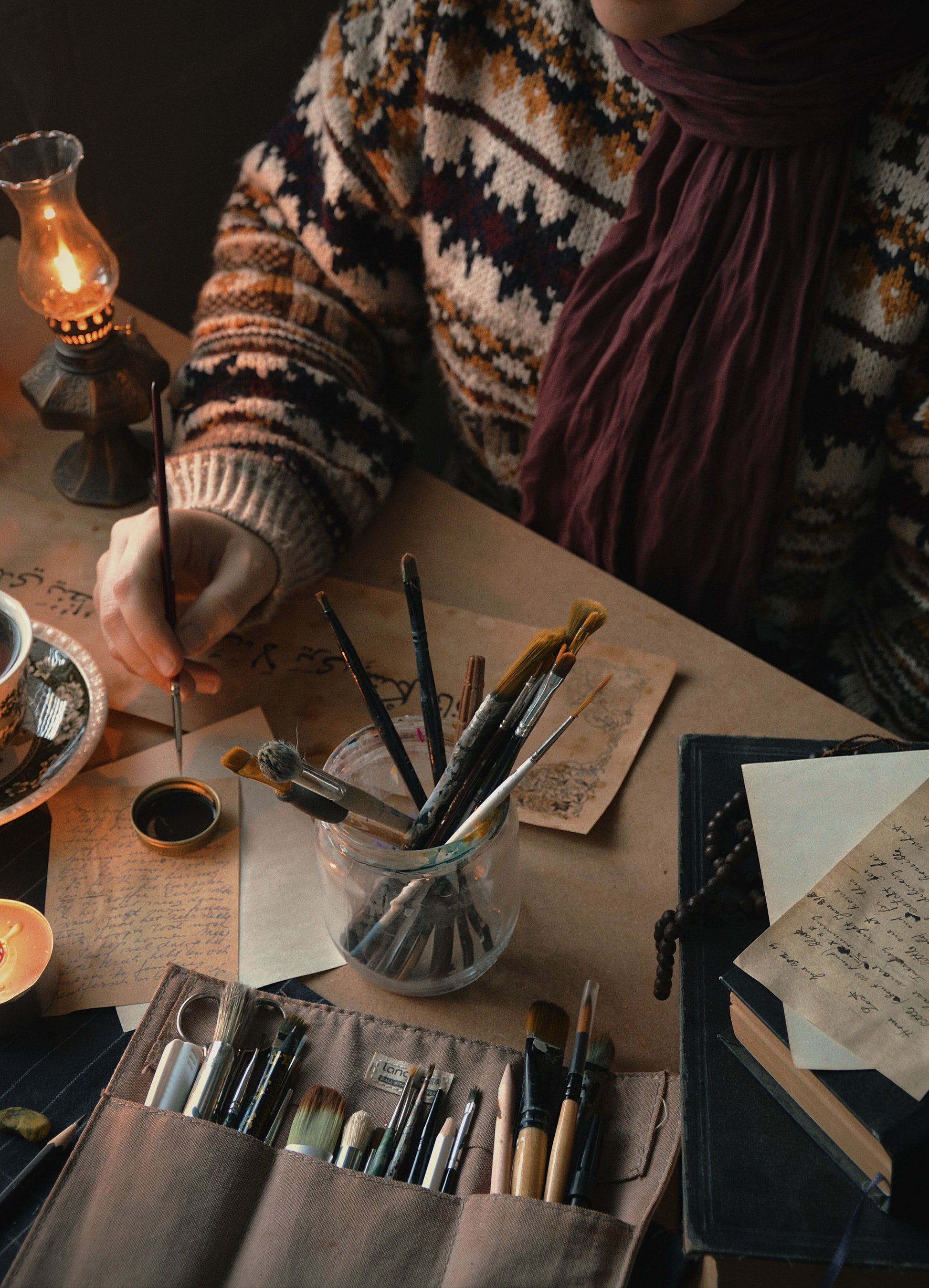 Person with painting supplies at a table with a warm, cozy atmosphere