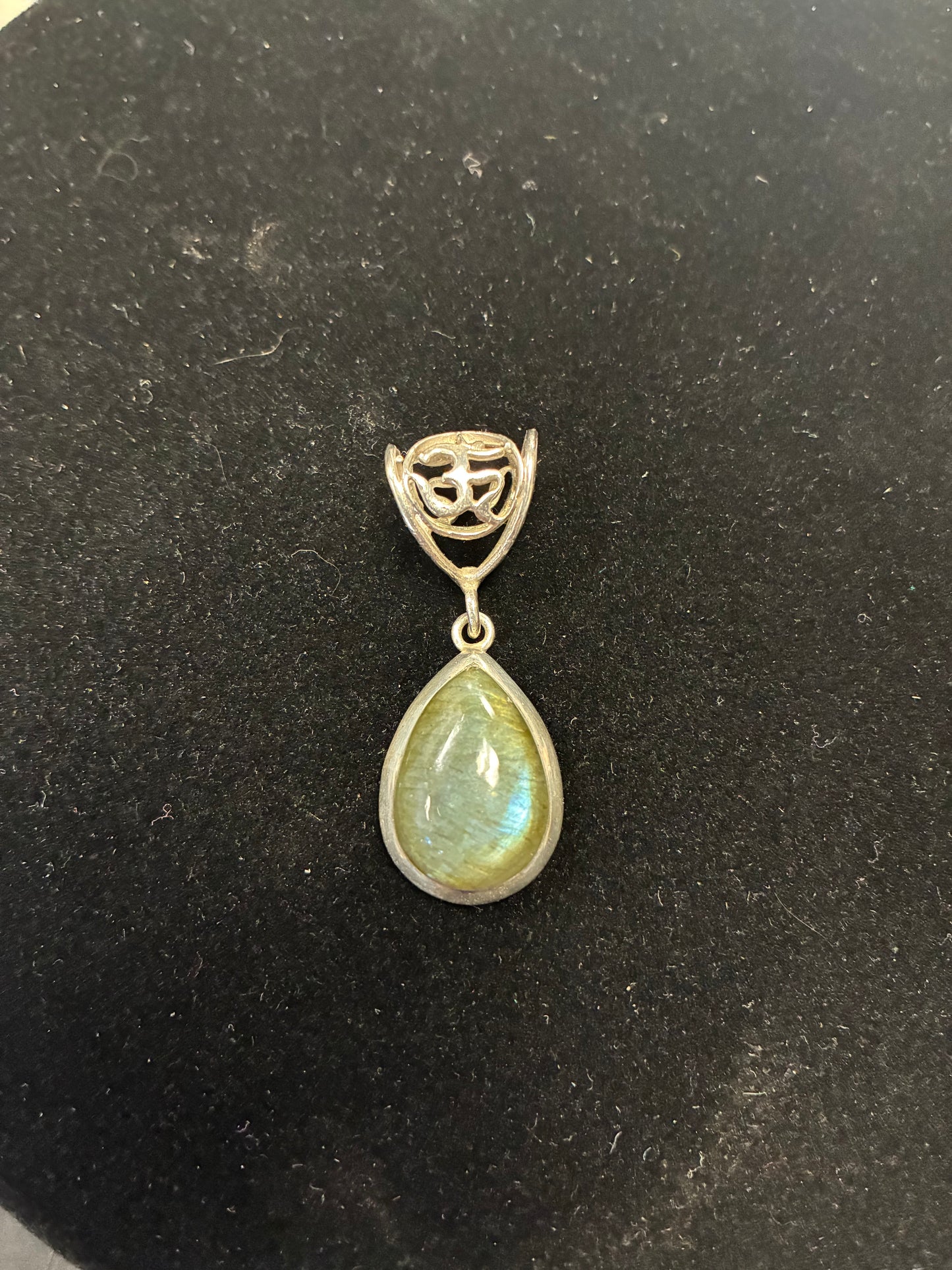 Teardrop-shaped gemstone pendant on a dark background