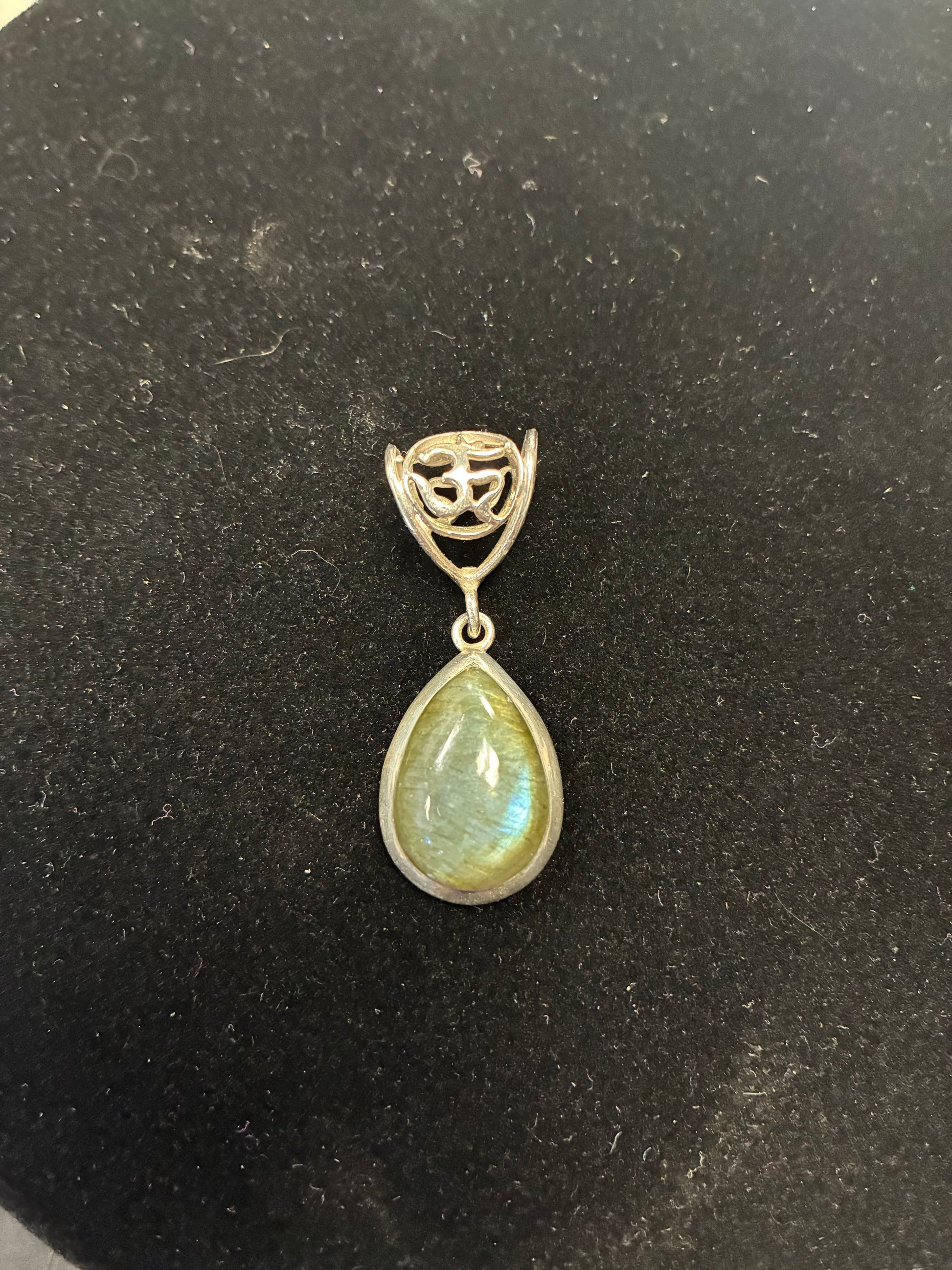 Teardrop-shaped gemstone pendant on a dark background