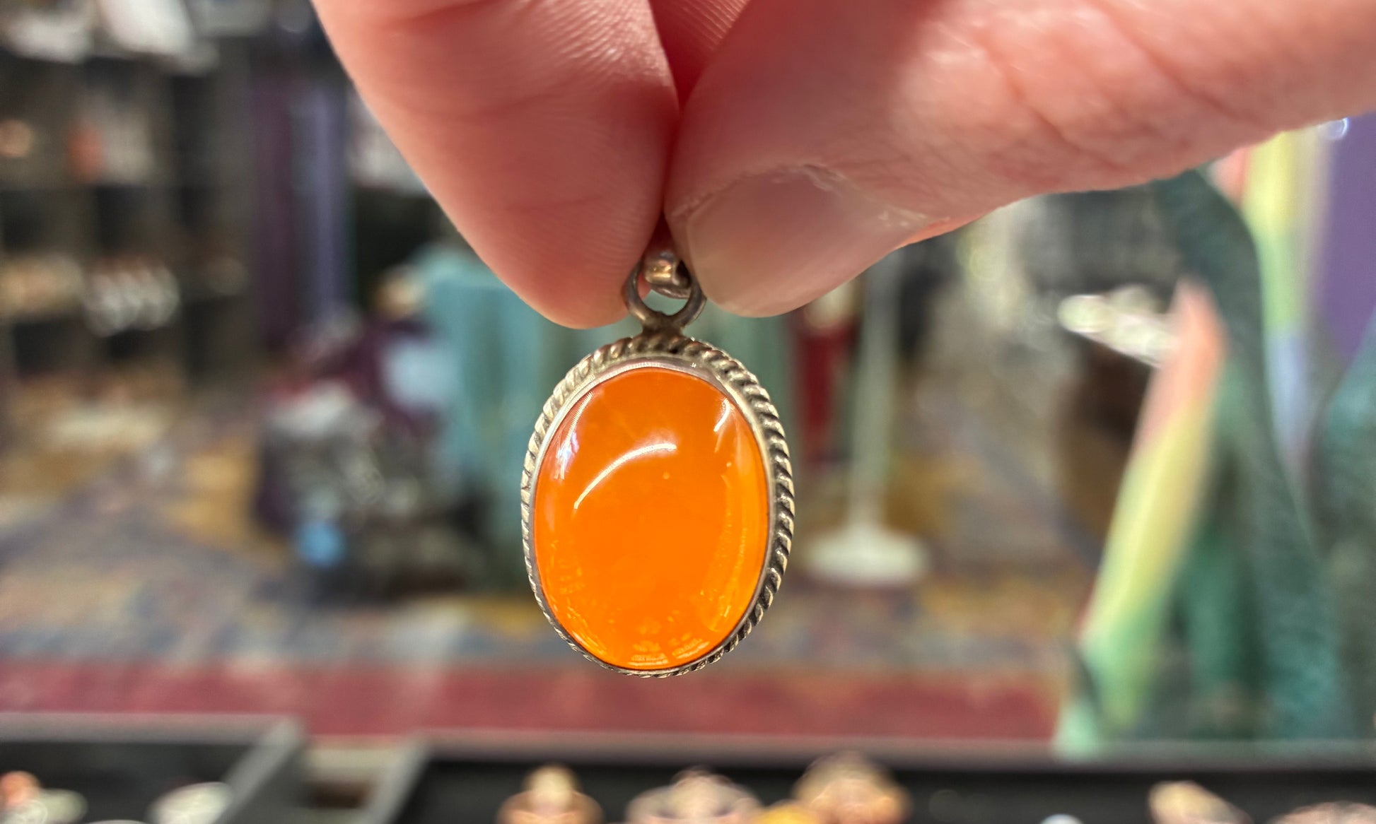 Hand holding an orange pendant with a blurred background